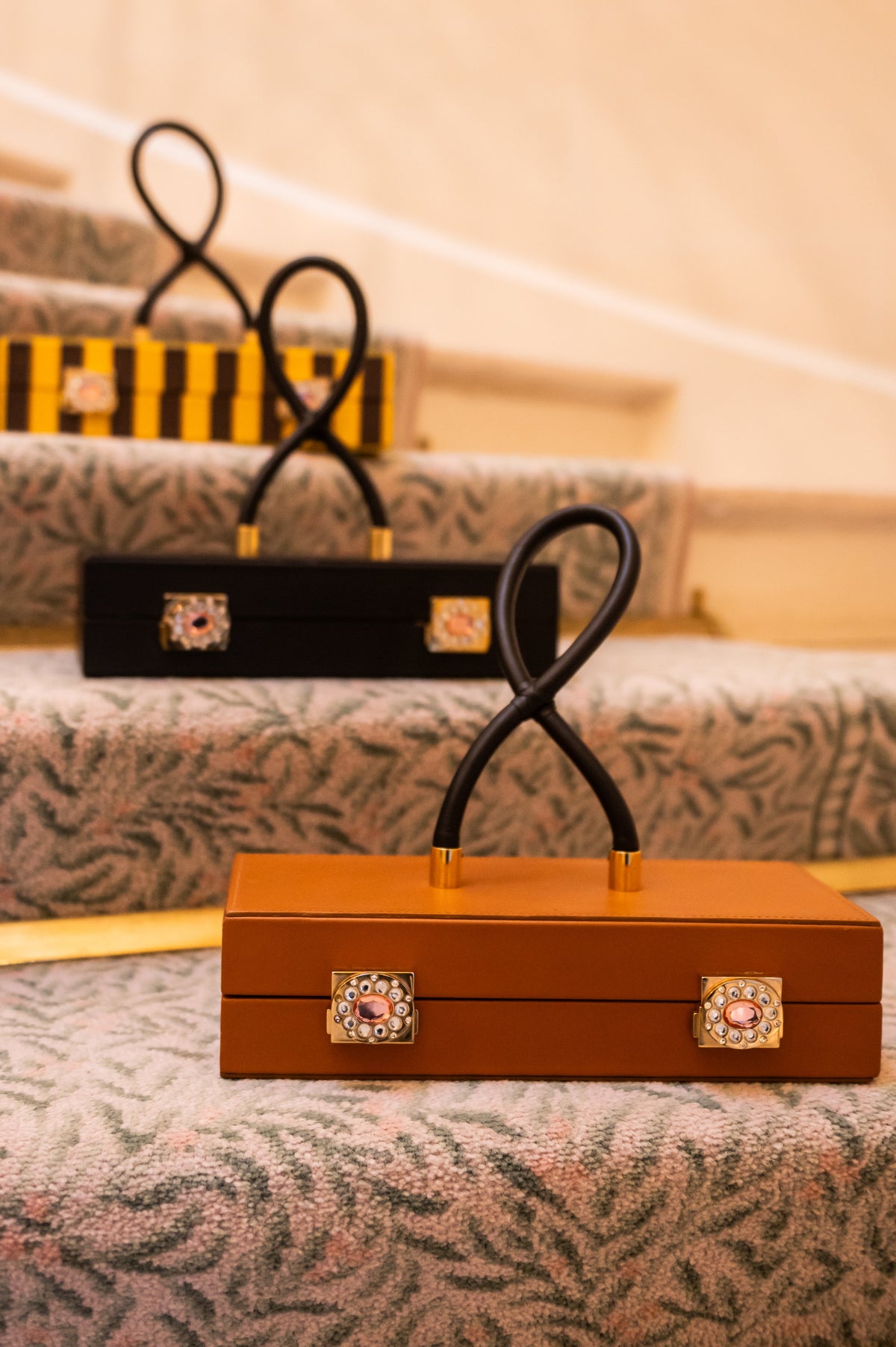 Trois sacs rectangulaires Moody Legacy disposés sur un escalier, avec un modèle caramel au premier plan.
